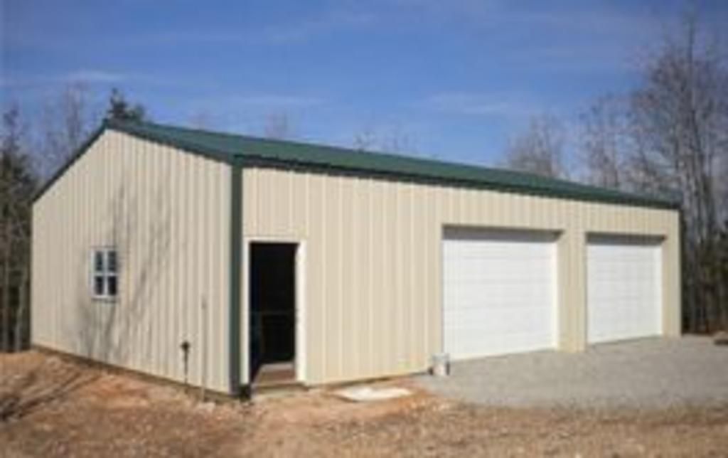 A metal garage with two garage doors and a green roof.