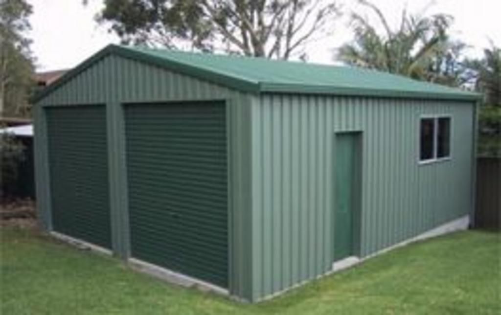 A green metal garage with two garage doors and two windows.