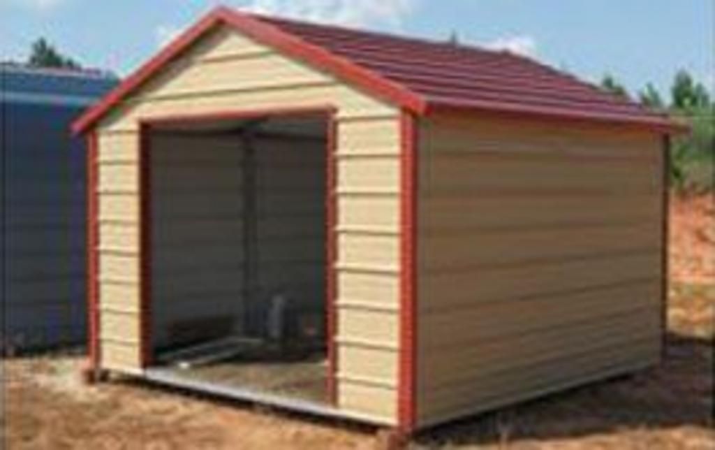 A small metal shed with a red roof is sitting in the dirt.