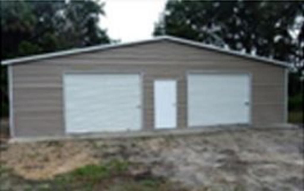 A garage with two garage doors and a door in the middle of a dirt field.