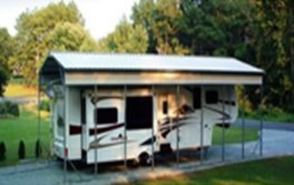 A trailer is parked under a canopy in a driveway.