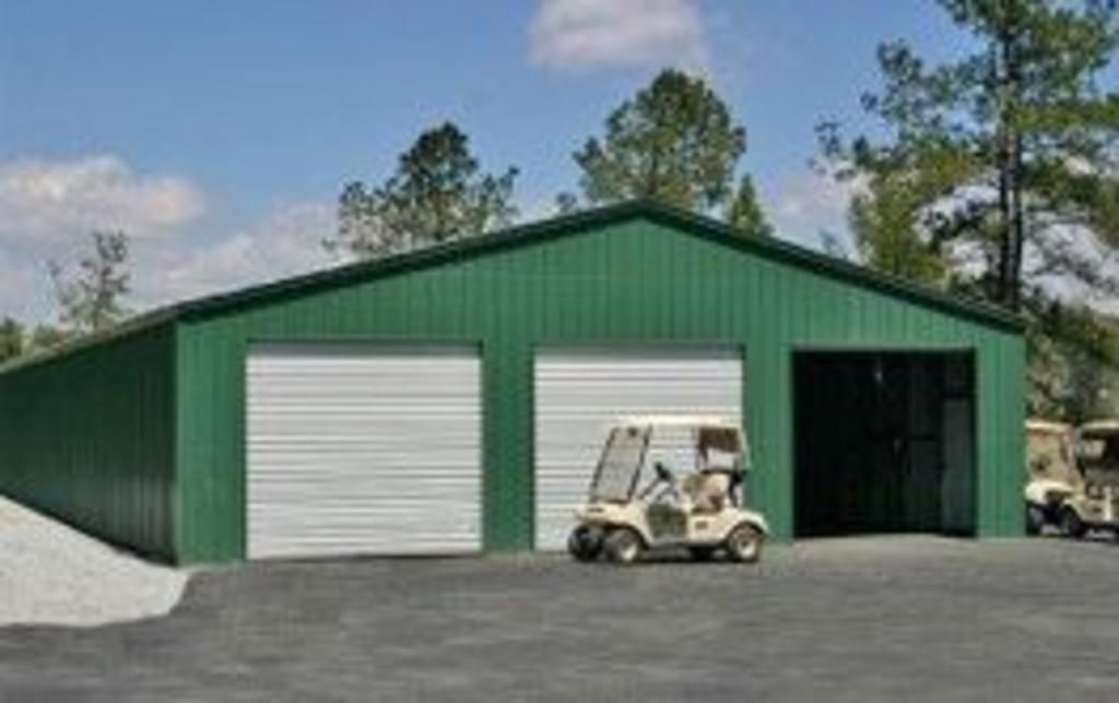 A golf cart is parked in front of a green garage.