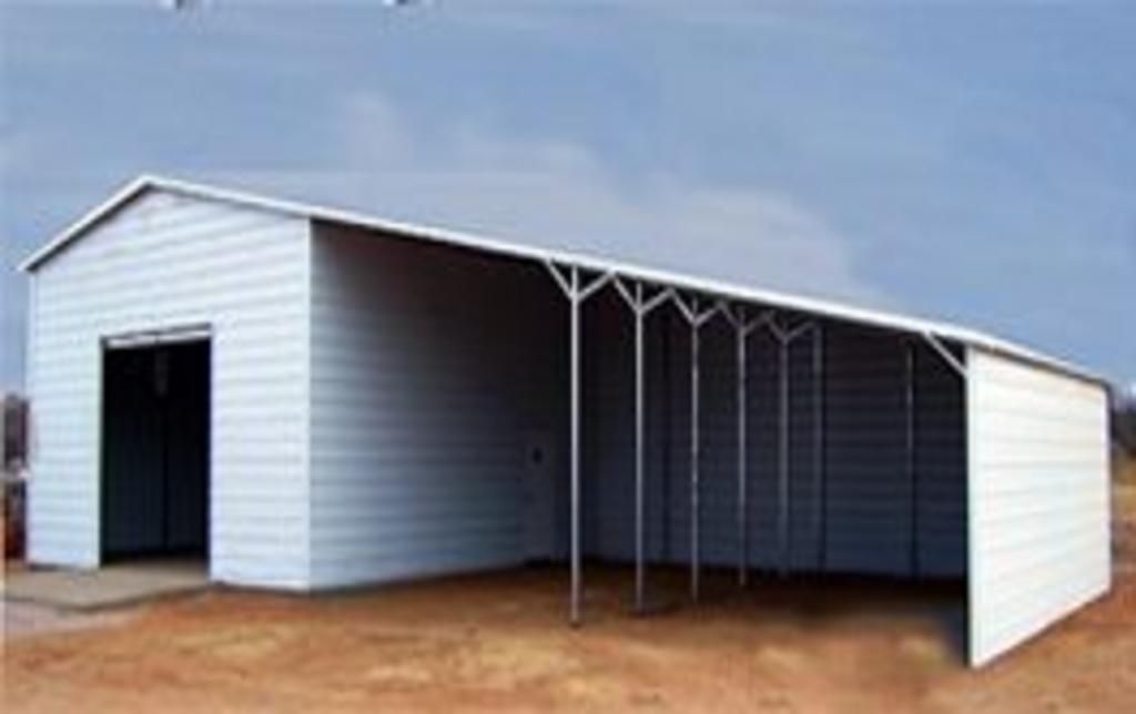 A white metal building with a canopy is sitting on top of a dirt field.