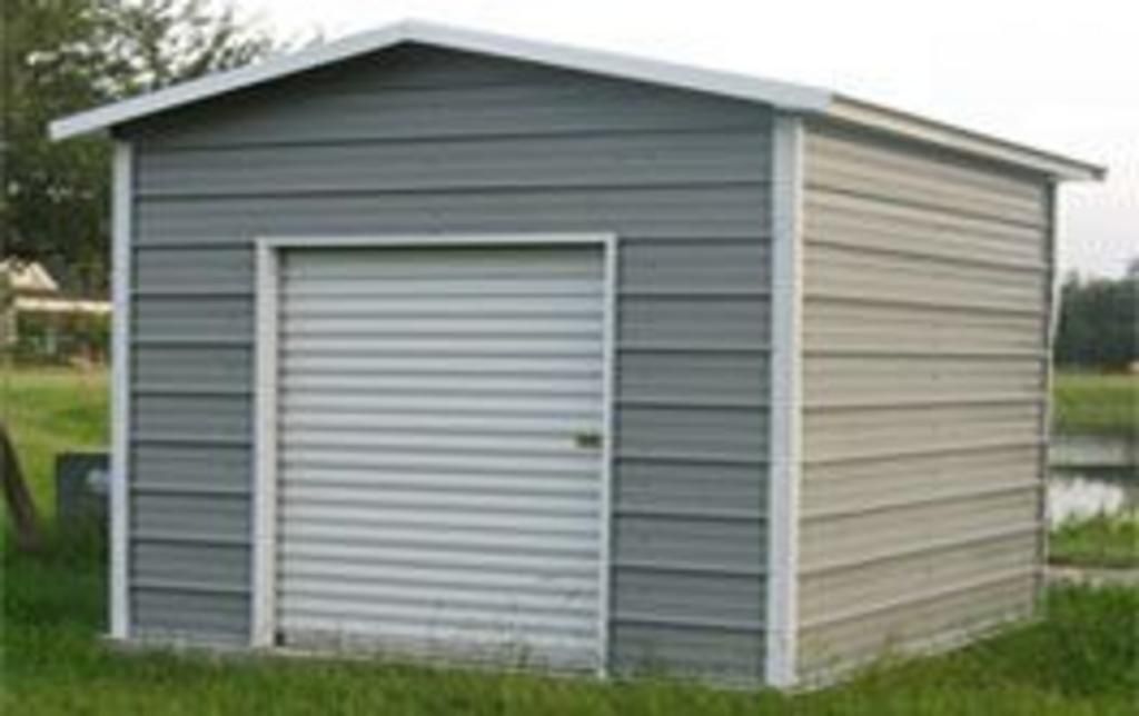 A small metal shed with a white door is sitting in the grass.