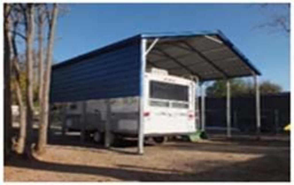 A white rv is parked under a blue carport.