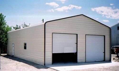 A white garage with two white garage doors and a blue sky in the background