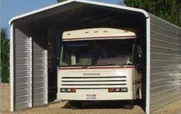 A white rv is parked in a metal garage.