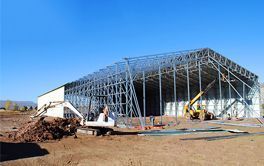 A large building is being built in the middle of a dirt field.