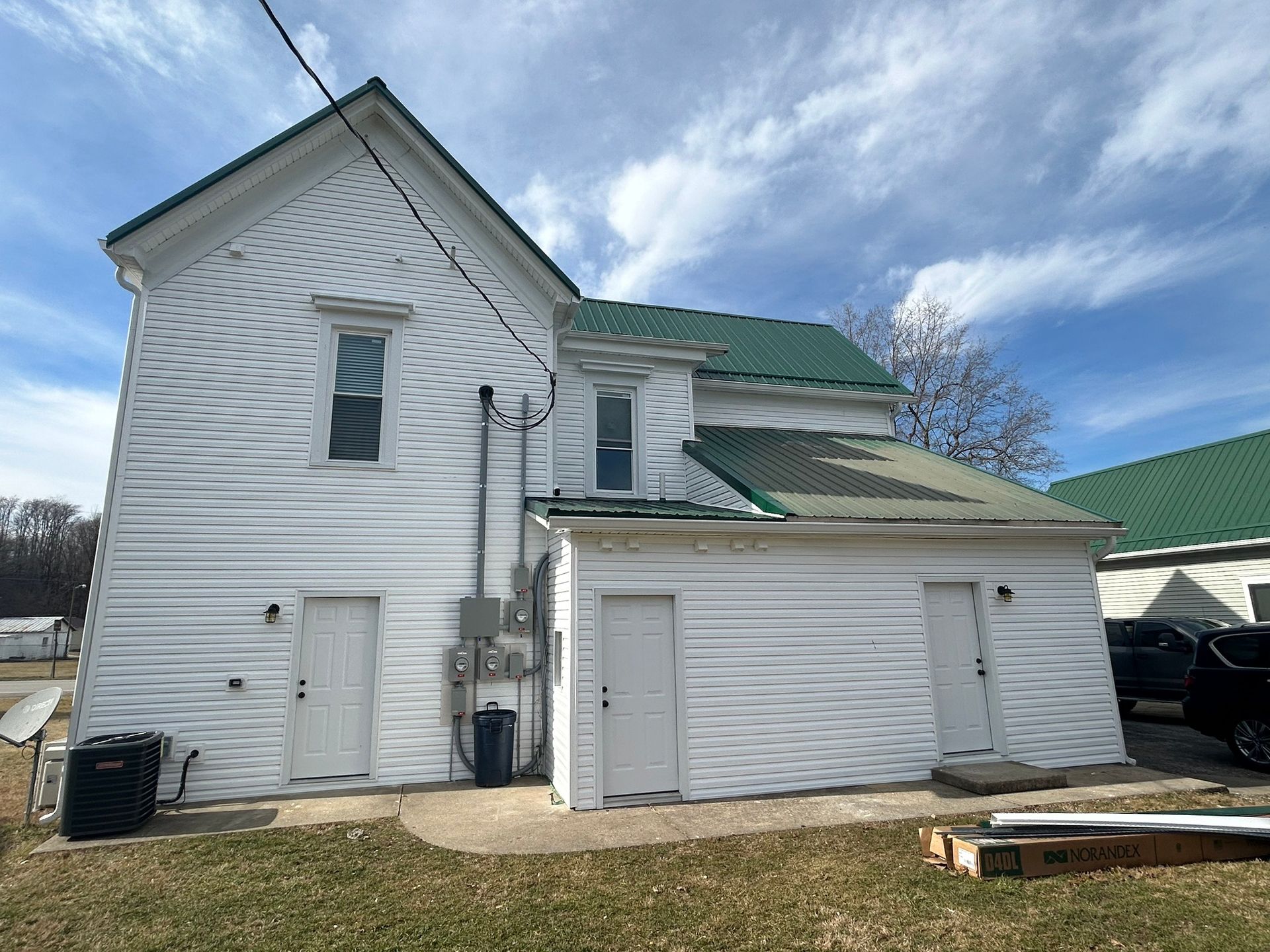 The back of a white house with a green roof.