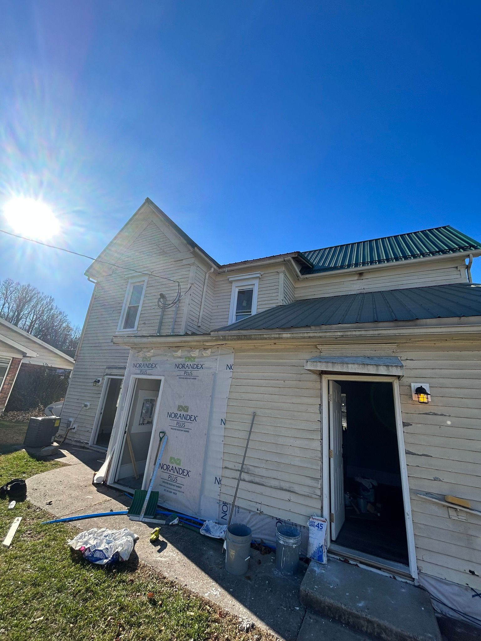 A white house with a blue sky in the background is being painted.