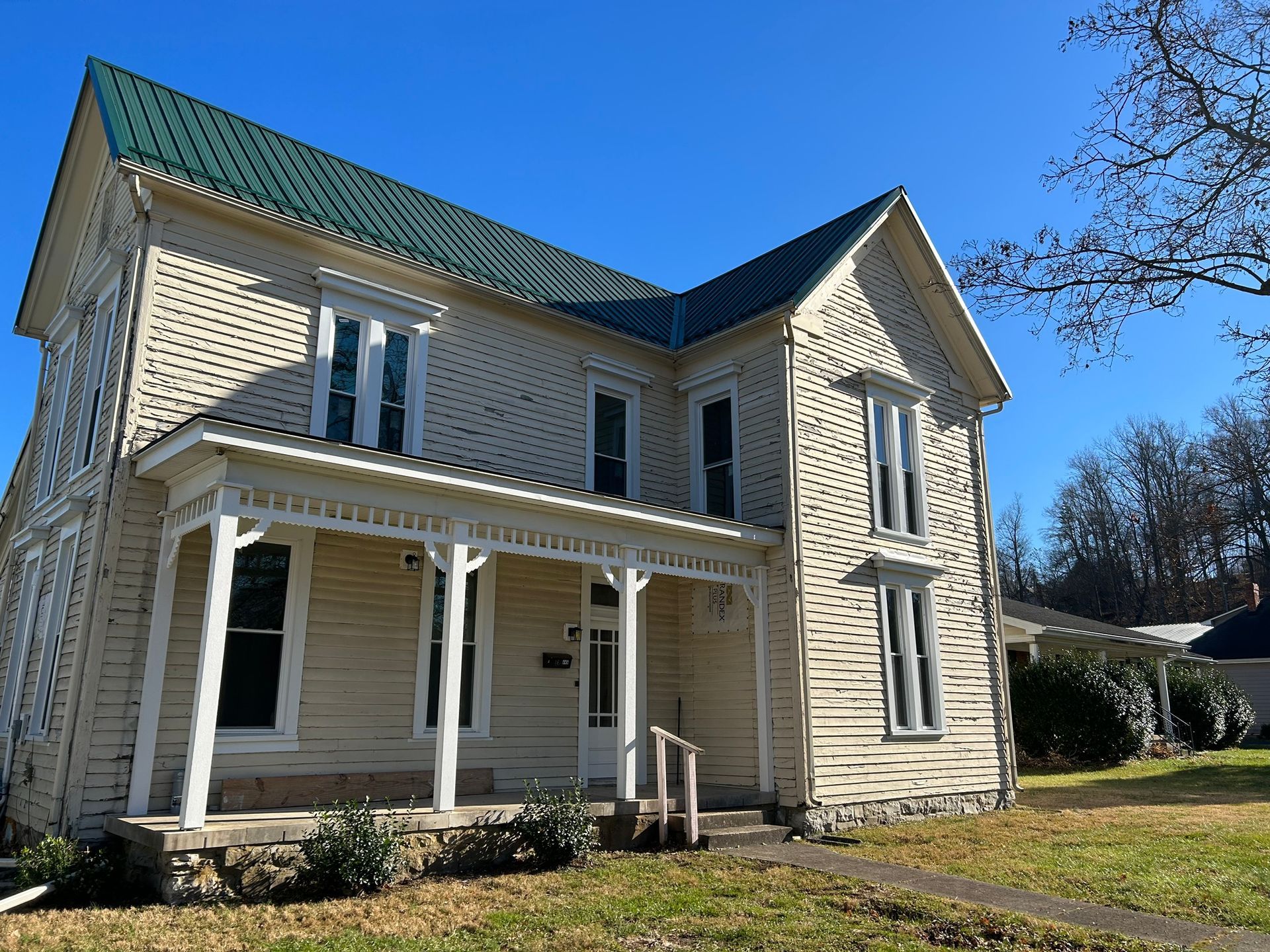 A white house with a green roof and a porch