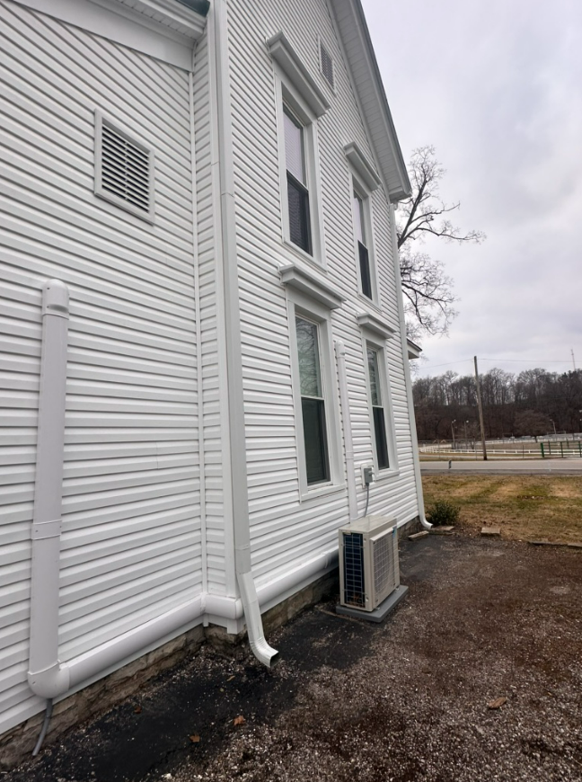 A white house with a drain pipe on the side of it.