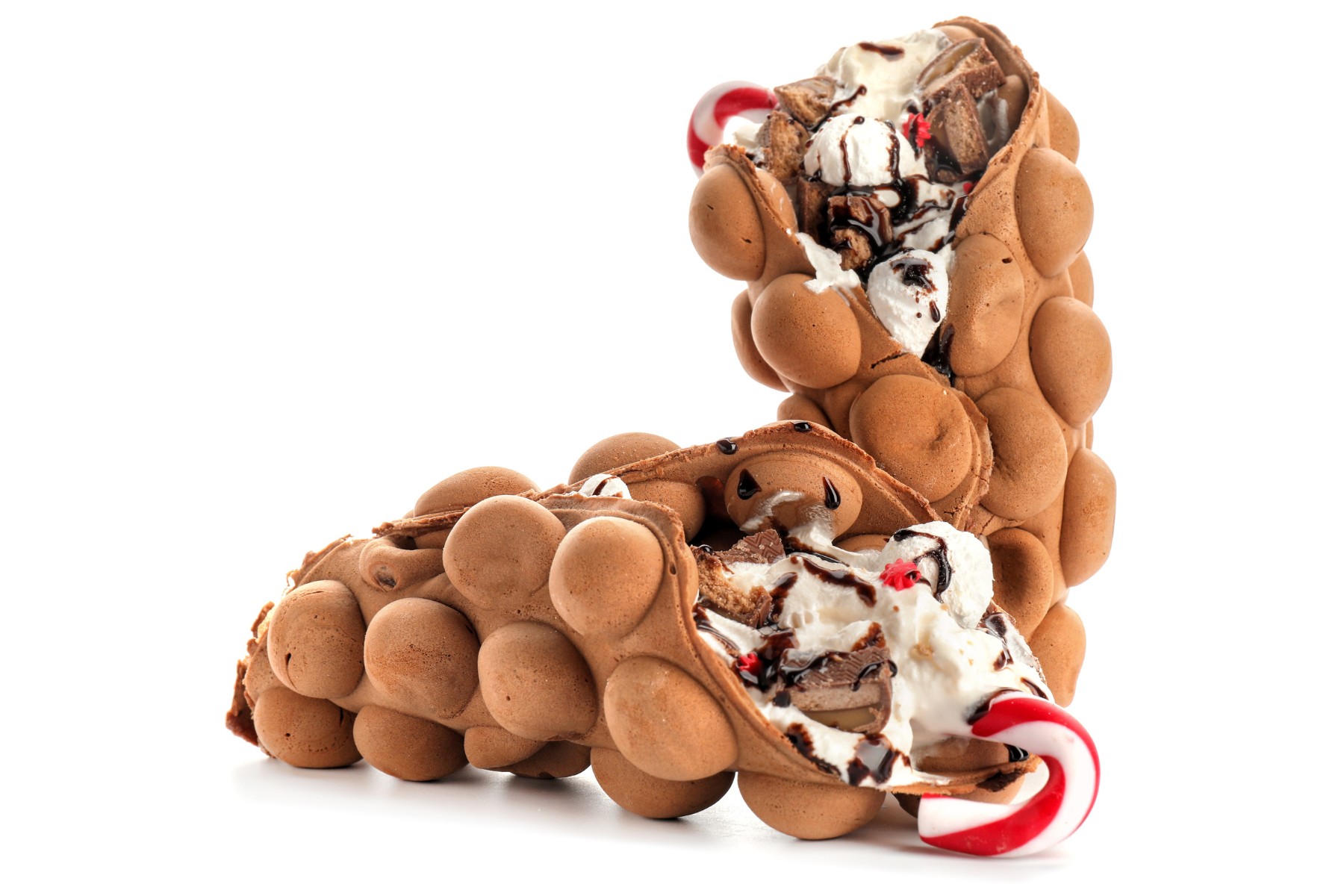 Two bubble waffles filled with ice cream, chocolate sauce, and candy canes.