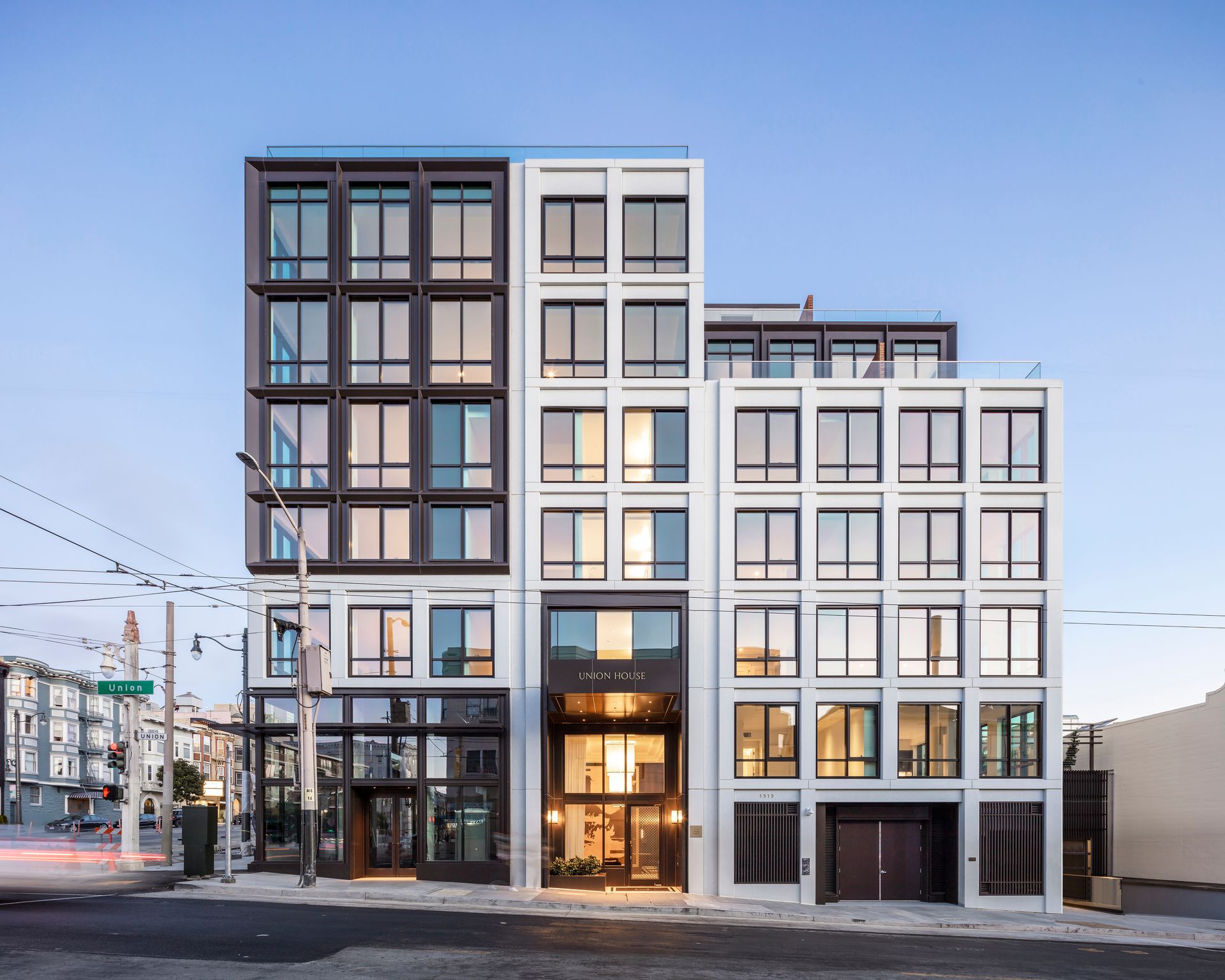 A large building with a lot of windows is on the corner of a street.