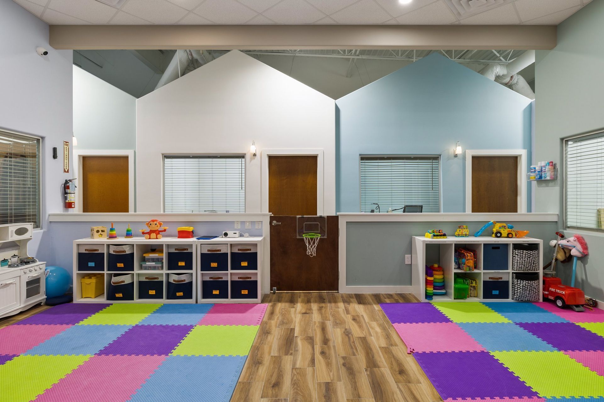 A room with a lot of toys on the floor and shelves.
