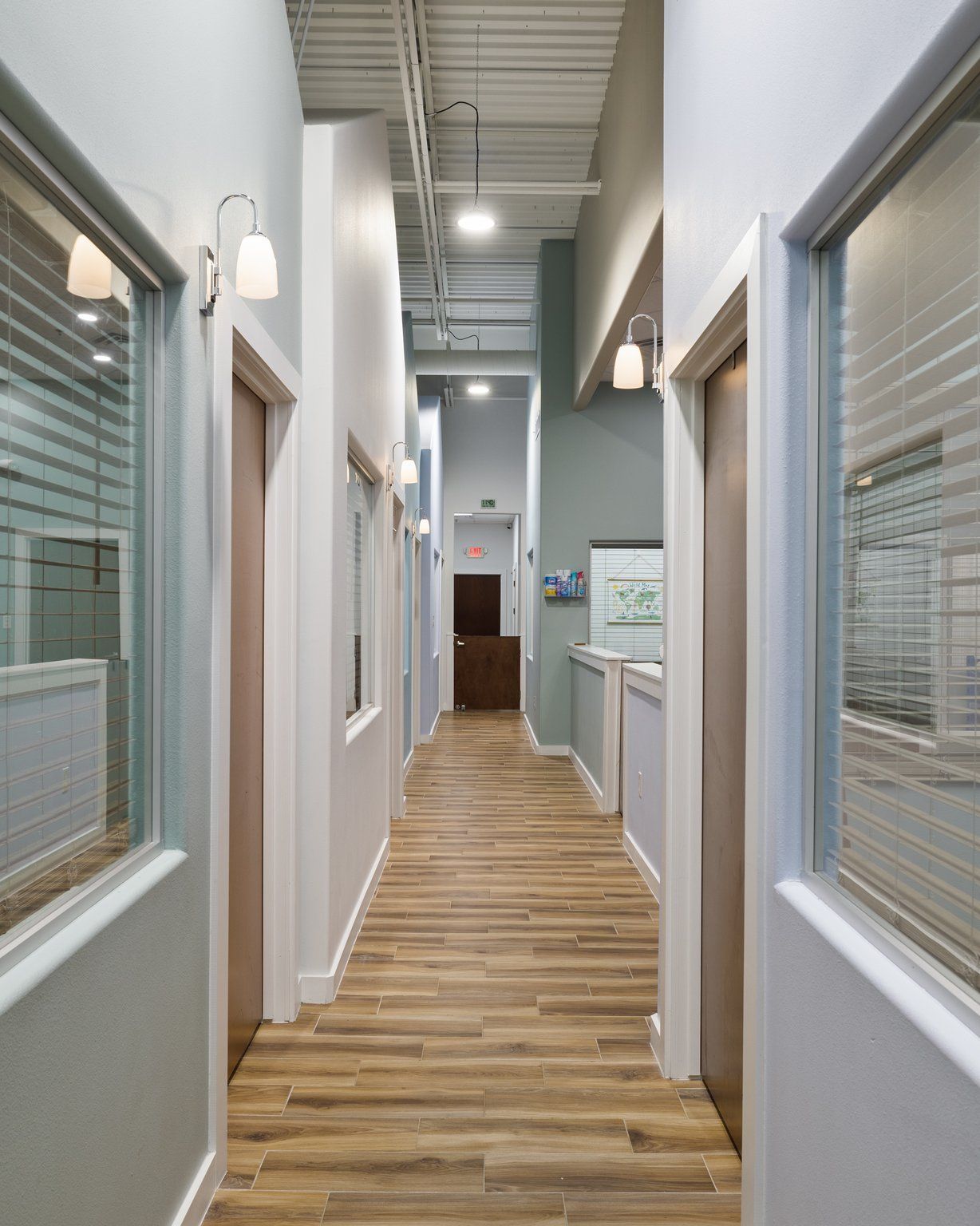 A long hallway with wooden floors and a lot of windows
