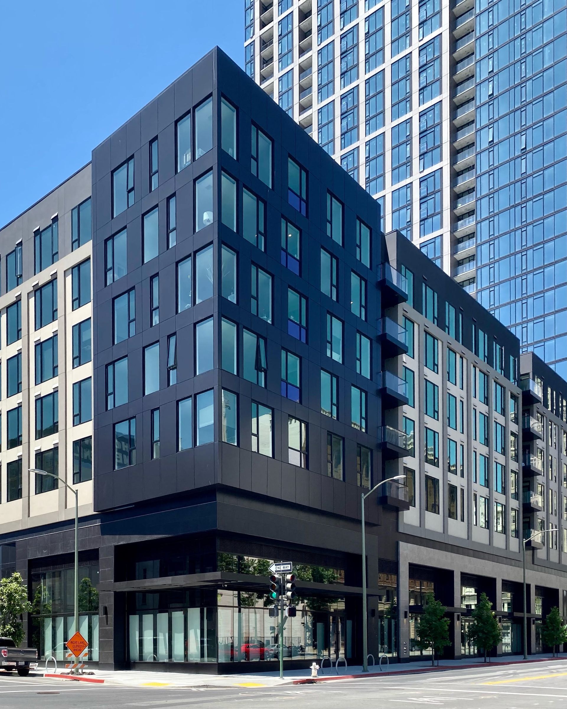 A large building with a lot of windows is sitting on the corner of a city street.