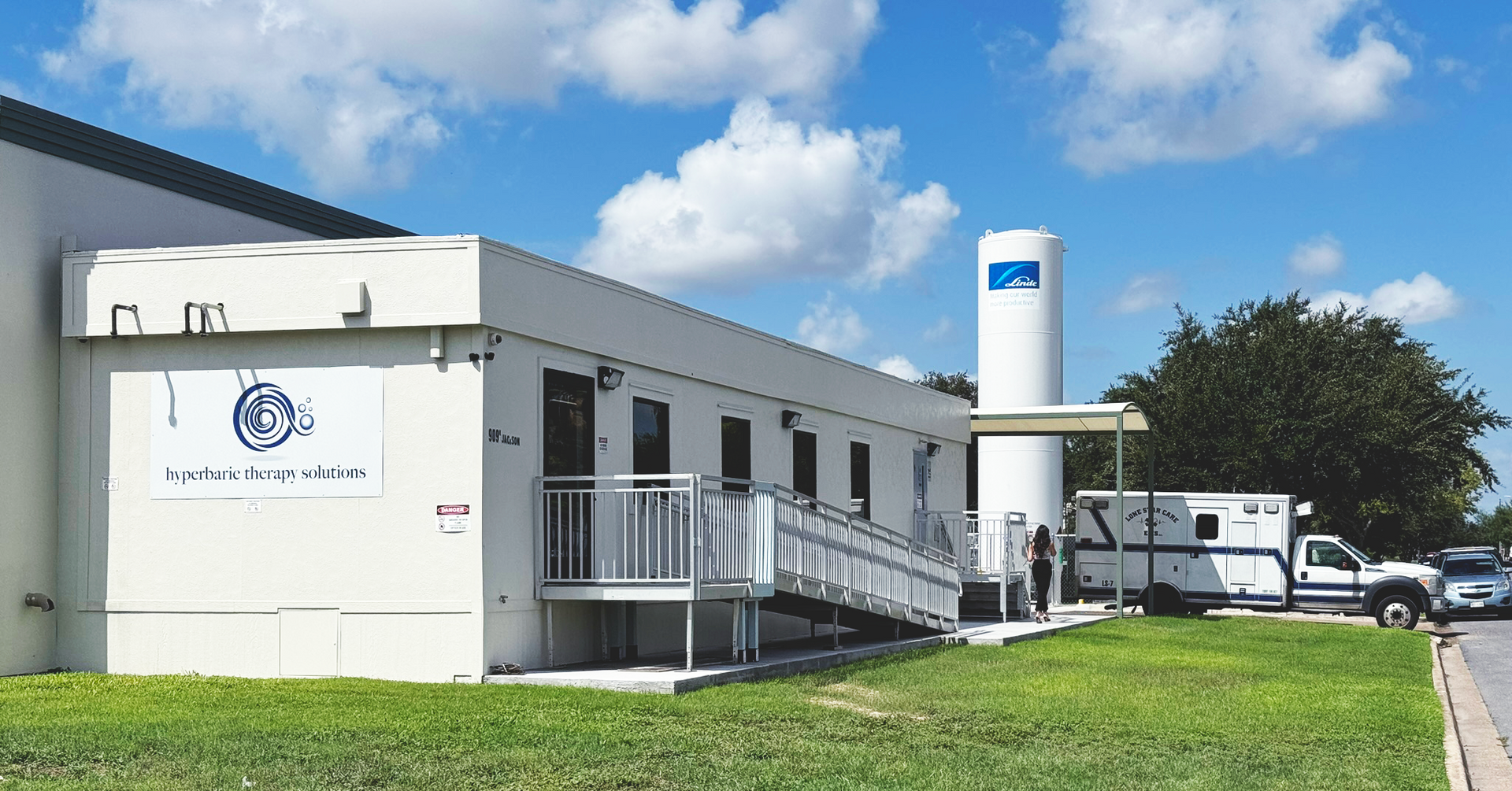 A white building with a green roof is on the side of the road