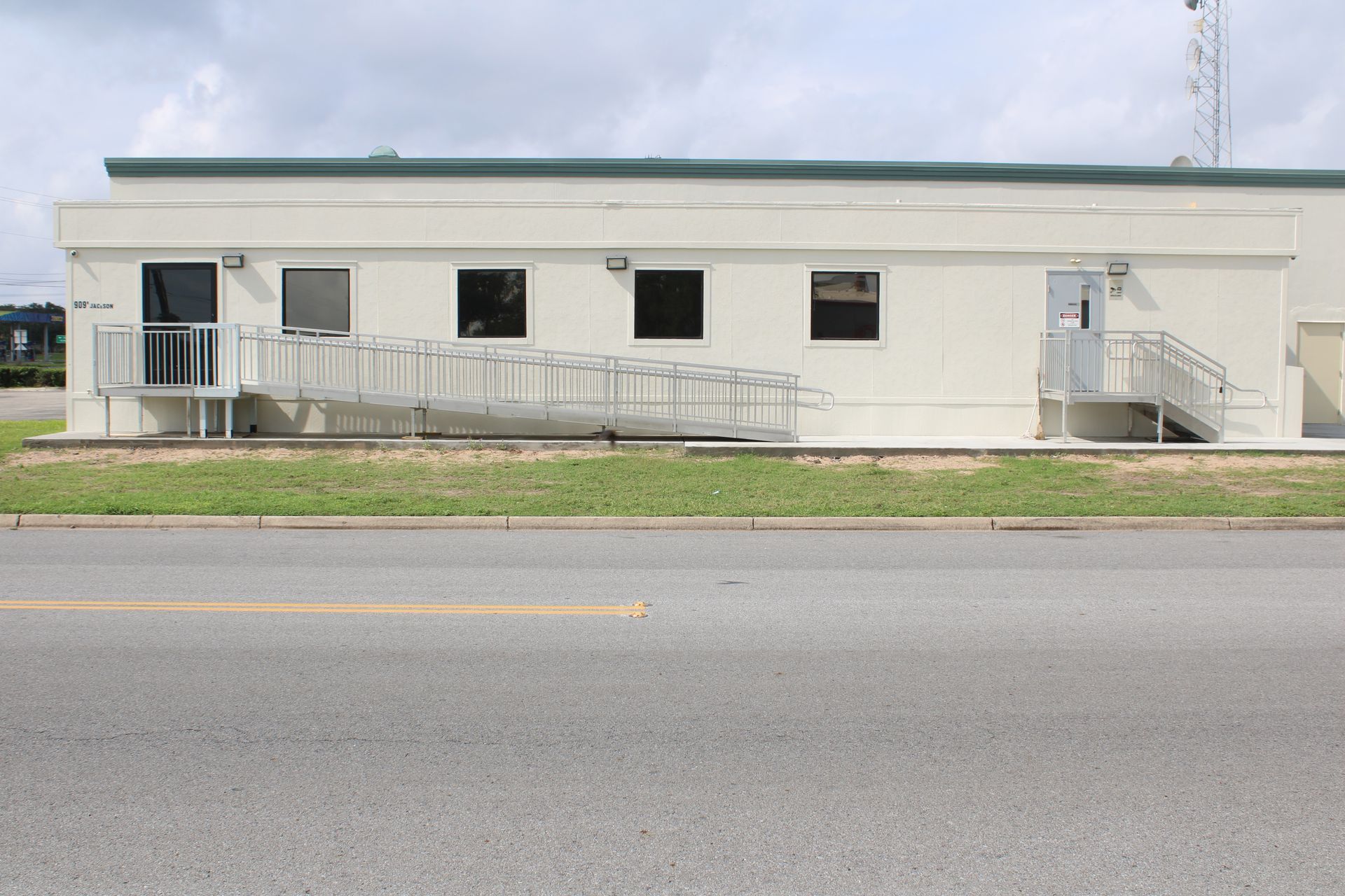 A white building with a ramp and stairs on the side of it.