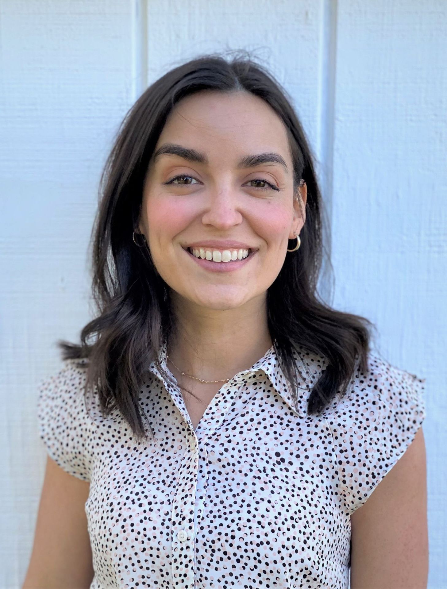 A woman in a polka dot shirt is smiling for the camera.
