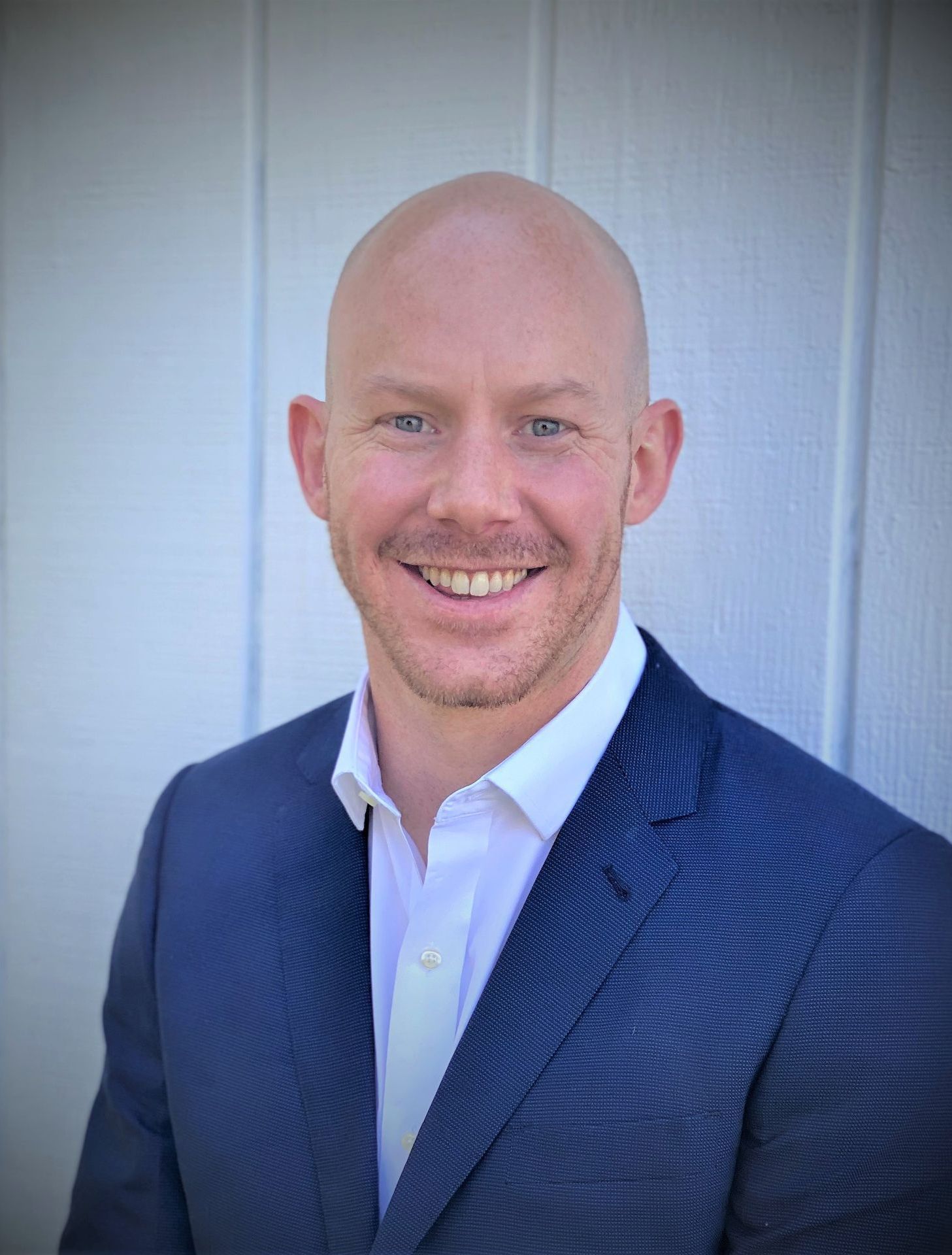 A man in a suit and white shirt is smiling for the camera.