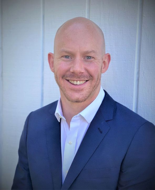 A man in a suit and white shirt is smiling for the camera.