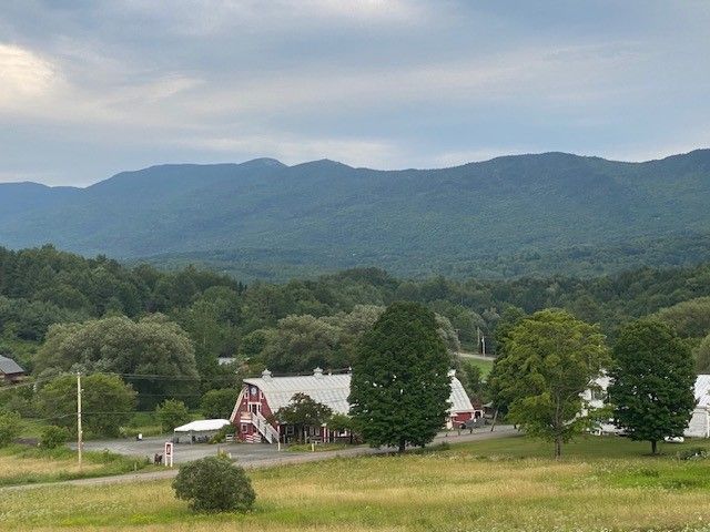 A red barn is in the middle of a field with in Waterbury, Vermont