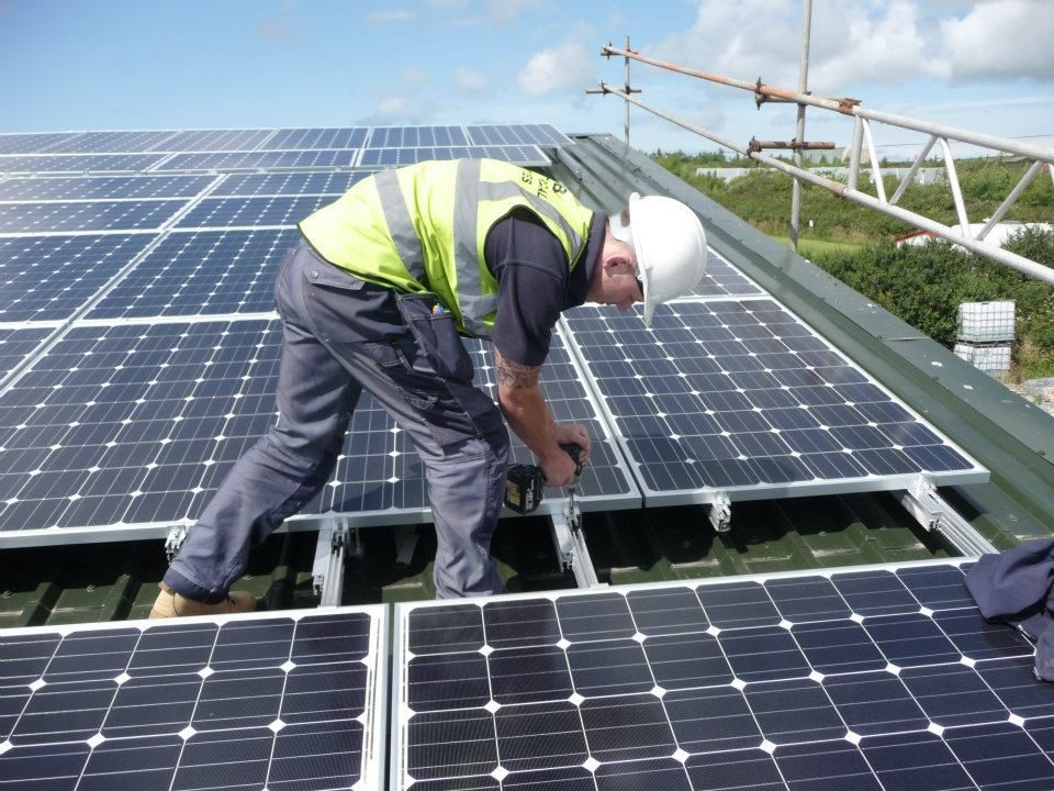 A man is working on solar panels on a roof