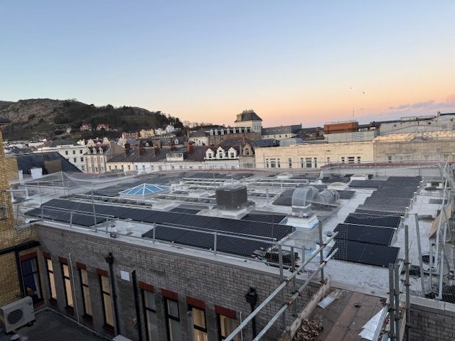 Rooftop HVAC units on a city building at sunset, with hills and waterfront in the background