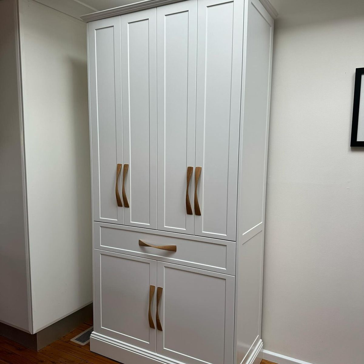 A White Cabinet With Wooden Handles And Drawers In A Room — Kreuzer Cabinets In East Wagga Wagga, NSW