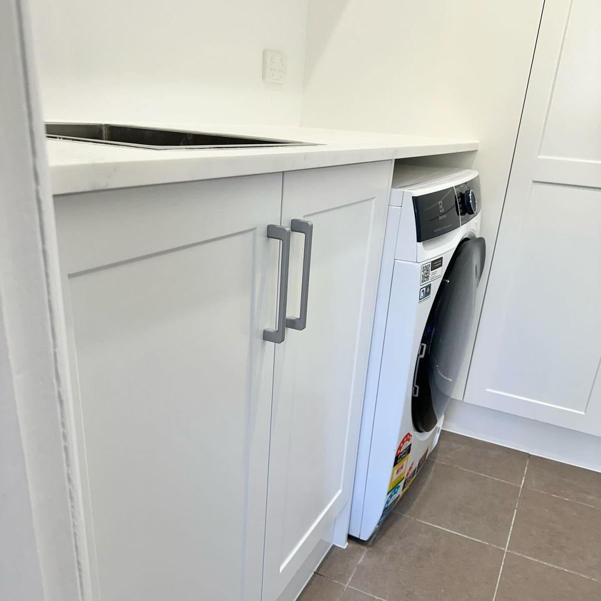 A Washer And Dryer Are In A Laundry Room With White Cabinets — Kreuzer Cabinets In East Wagga Wagga, NSW