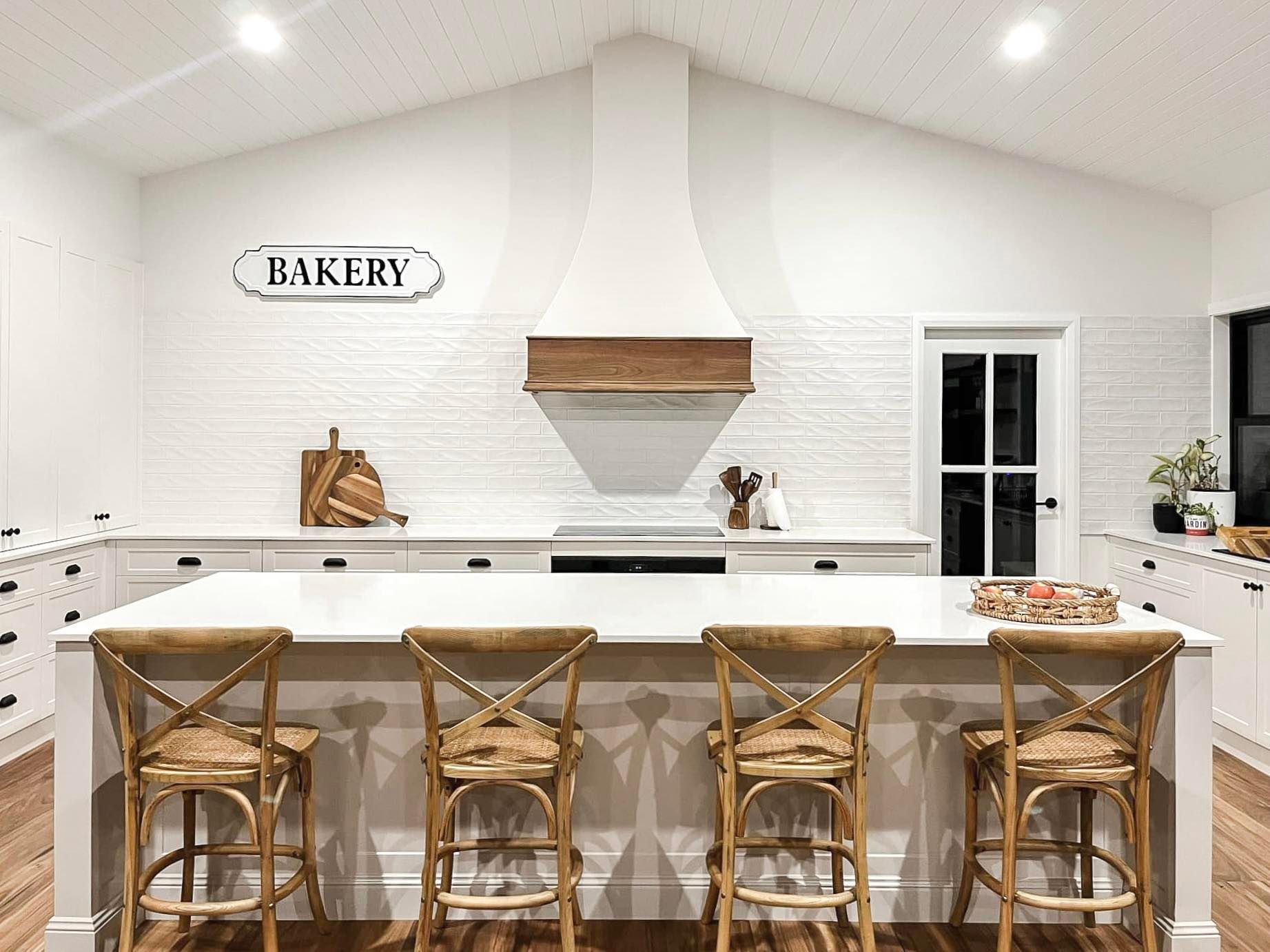 A Kitchen With a Large Island and Wooden Stools — Kreuzer Cabinets In East Wagga Wagga, NSW