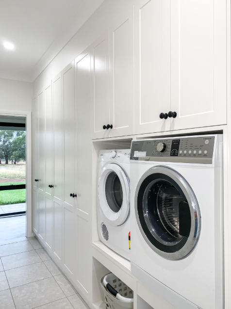 A Laundry Room With a Washer and Dryer Stacked on Top of Each Other — Kreuzer Cabinets In East Wagga Wagga, NSW