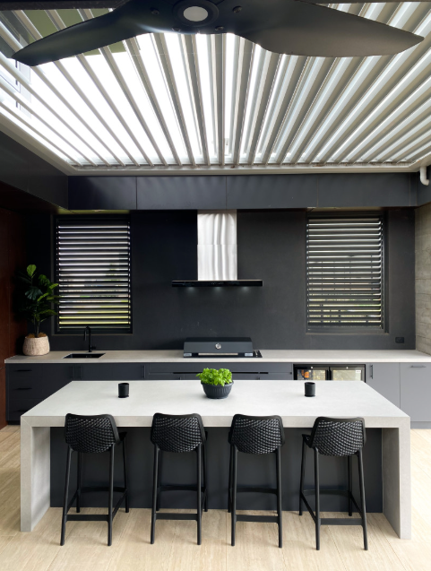 A Kitchen With a Large Island and Stools Under a Ceiling Fan — Kreuzer Cabinets In East Wagga Wagga, NSW