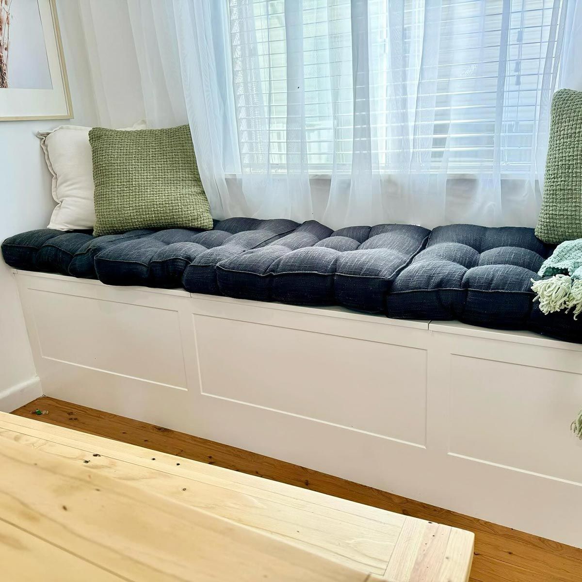 A Window Seat With A Black Cushion And Green Pillows In A Living Room — Kreuzer Cabinets In East Wagga Wagga, NSW