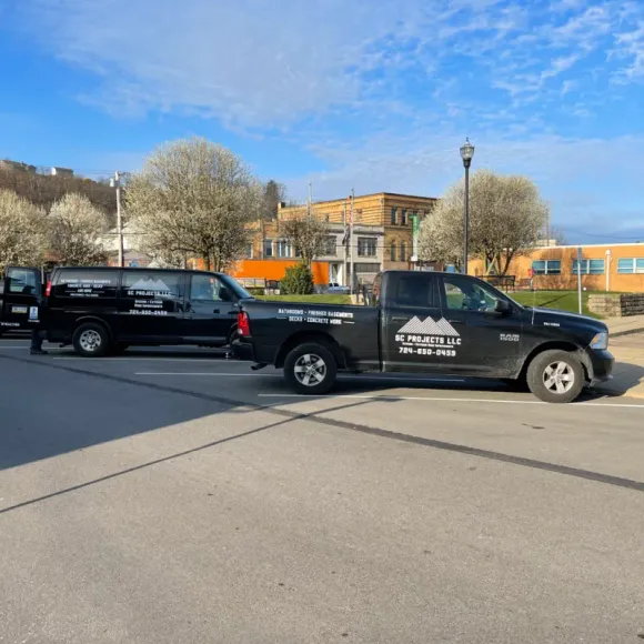 A truck with a mountain on the side is parked next to a van