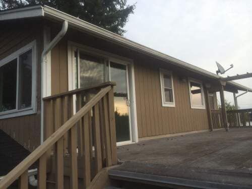 Brown house with white trim, deck, sliding glass door, and a satellite dish.