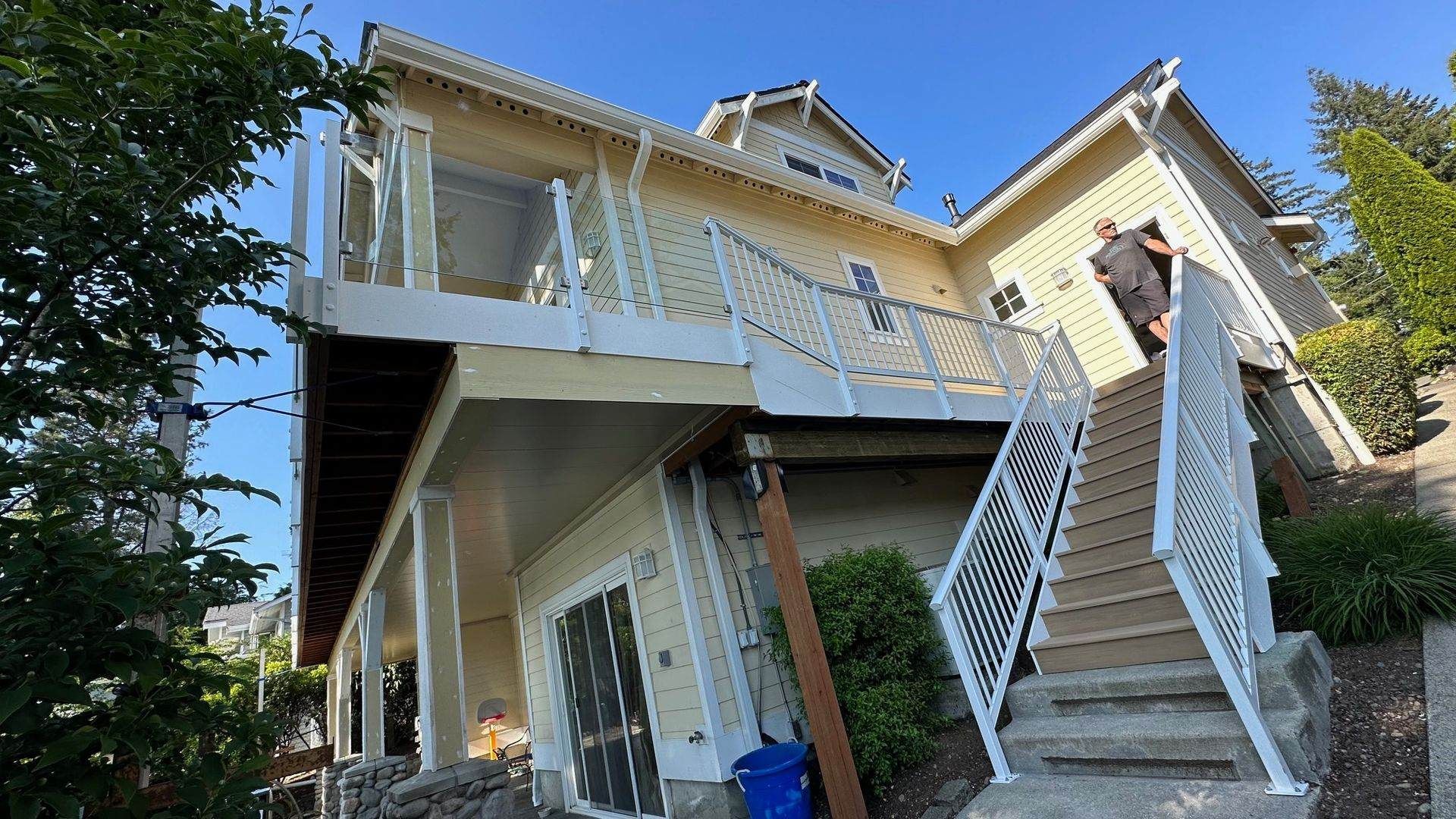 Yellow house with two-story deck, stairs, and a person walking up the stairs.