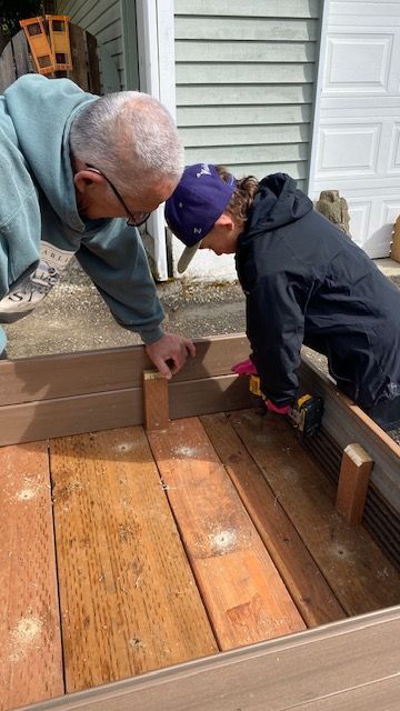 Man and person building a wooden structure together outdoors.