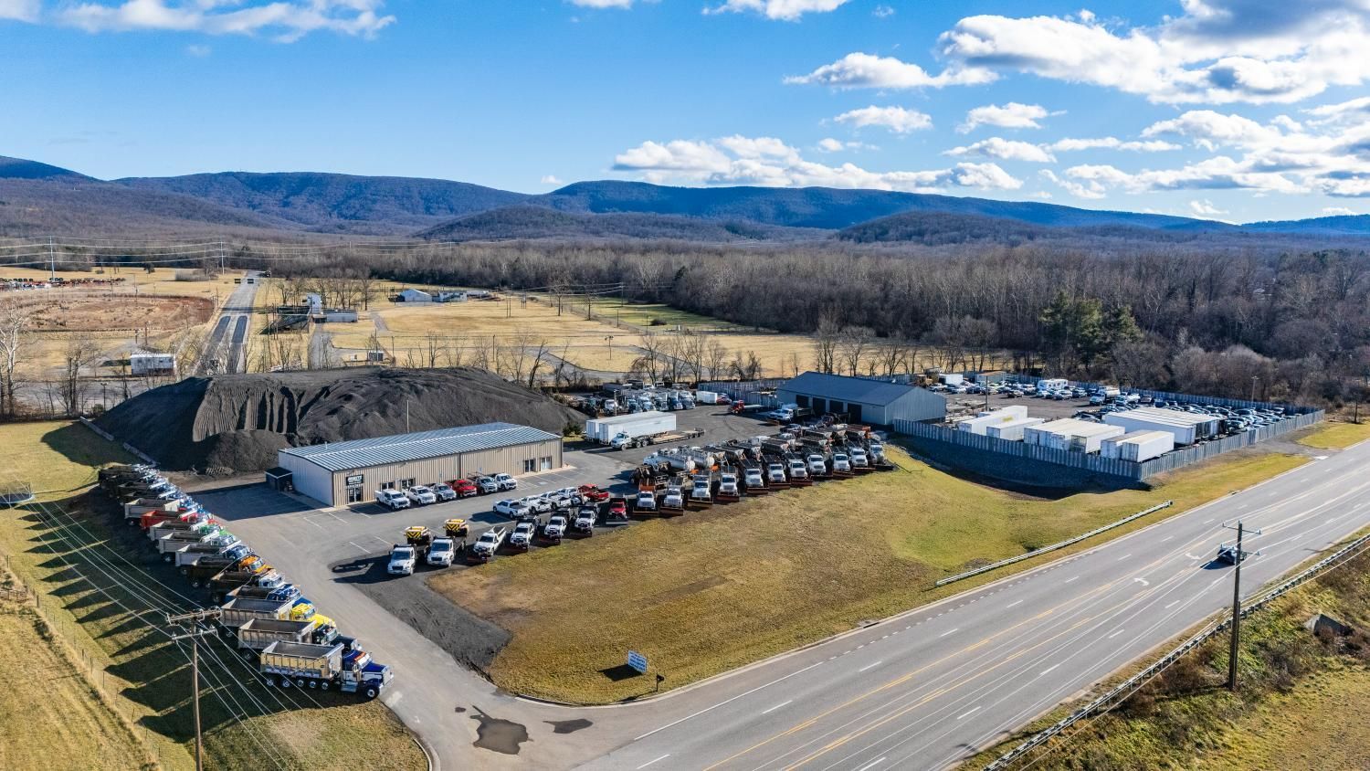 An aerial view of a car dealership with a lot of cars parked in front of it.