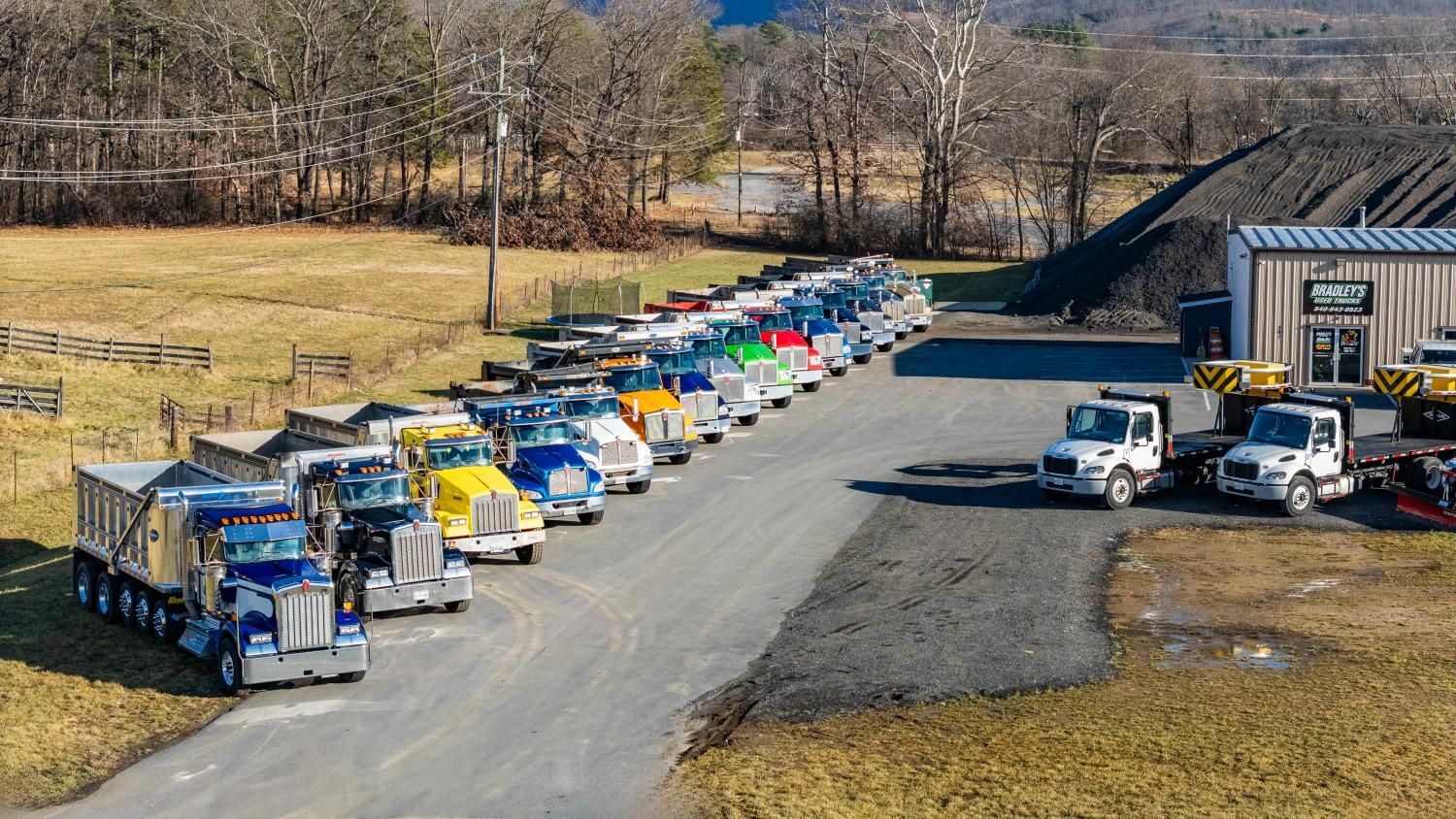 A row of trucks are parked on the side of a road.