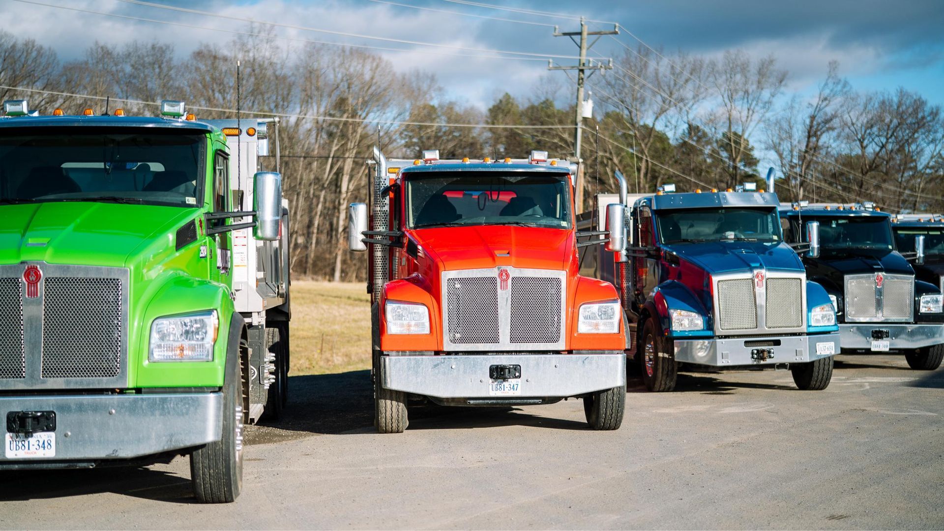 A row of trucks are parked next to each other in a parking lot.
