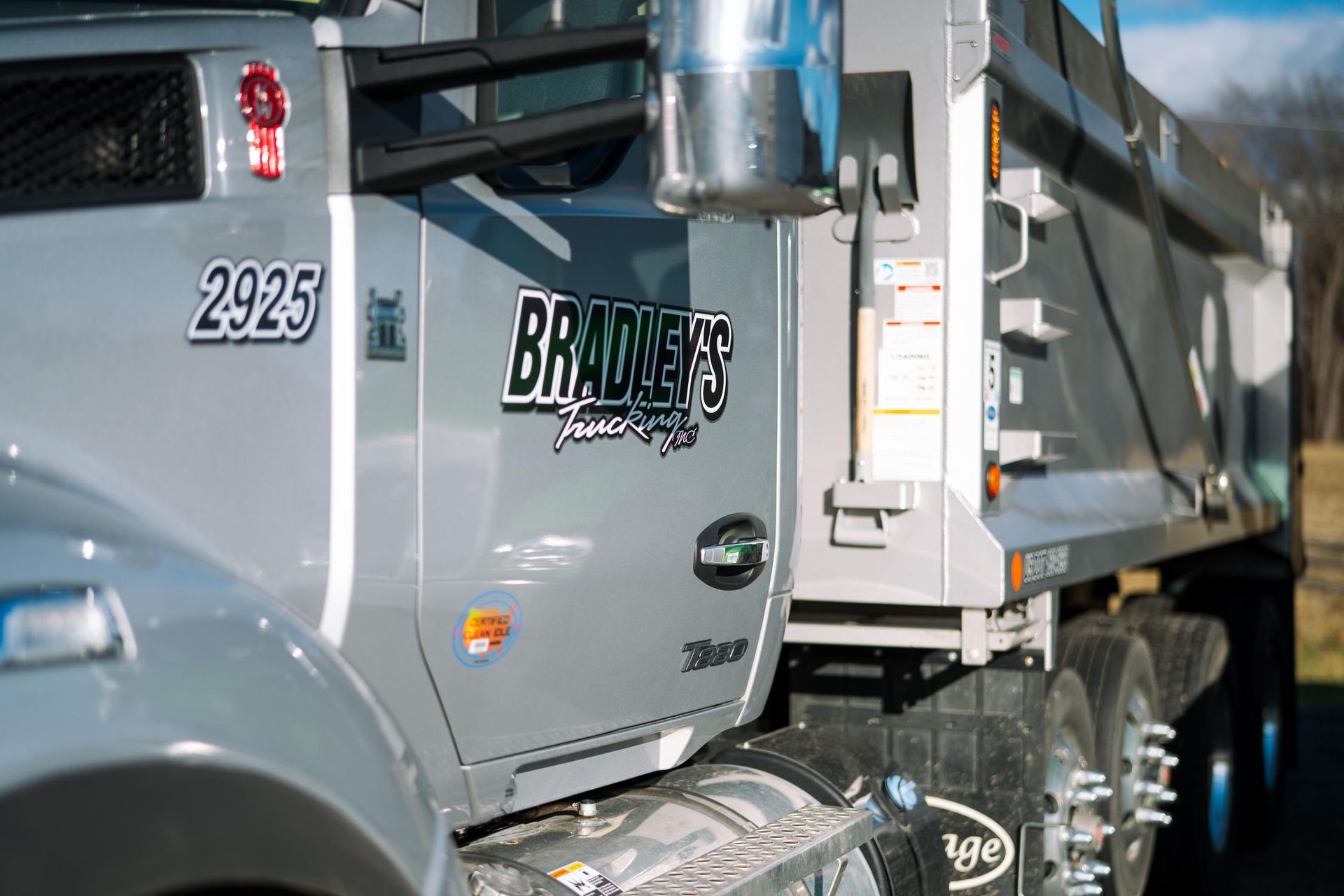 A dump truck with the number 2925 on the side is parked in a field.