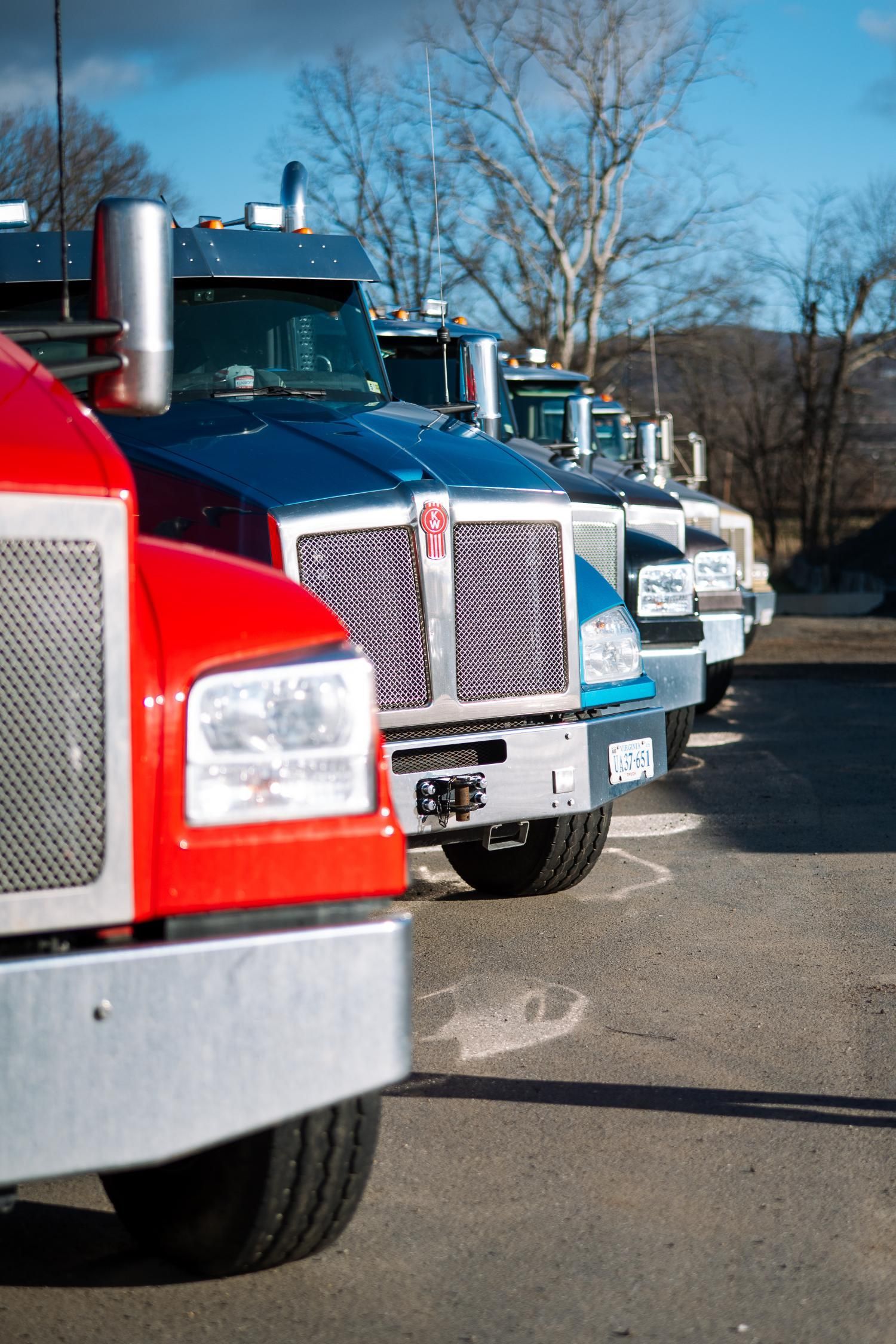 A row of semi trucks are parked in a parking lot.