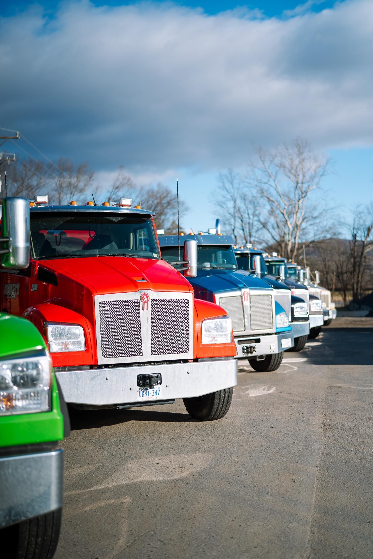 A row of semi trucks are parked in a parking lot.