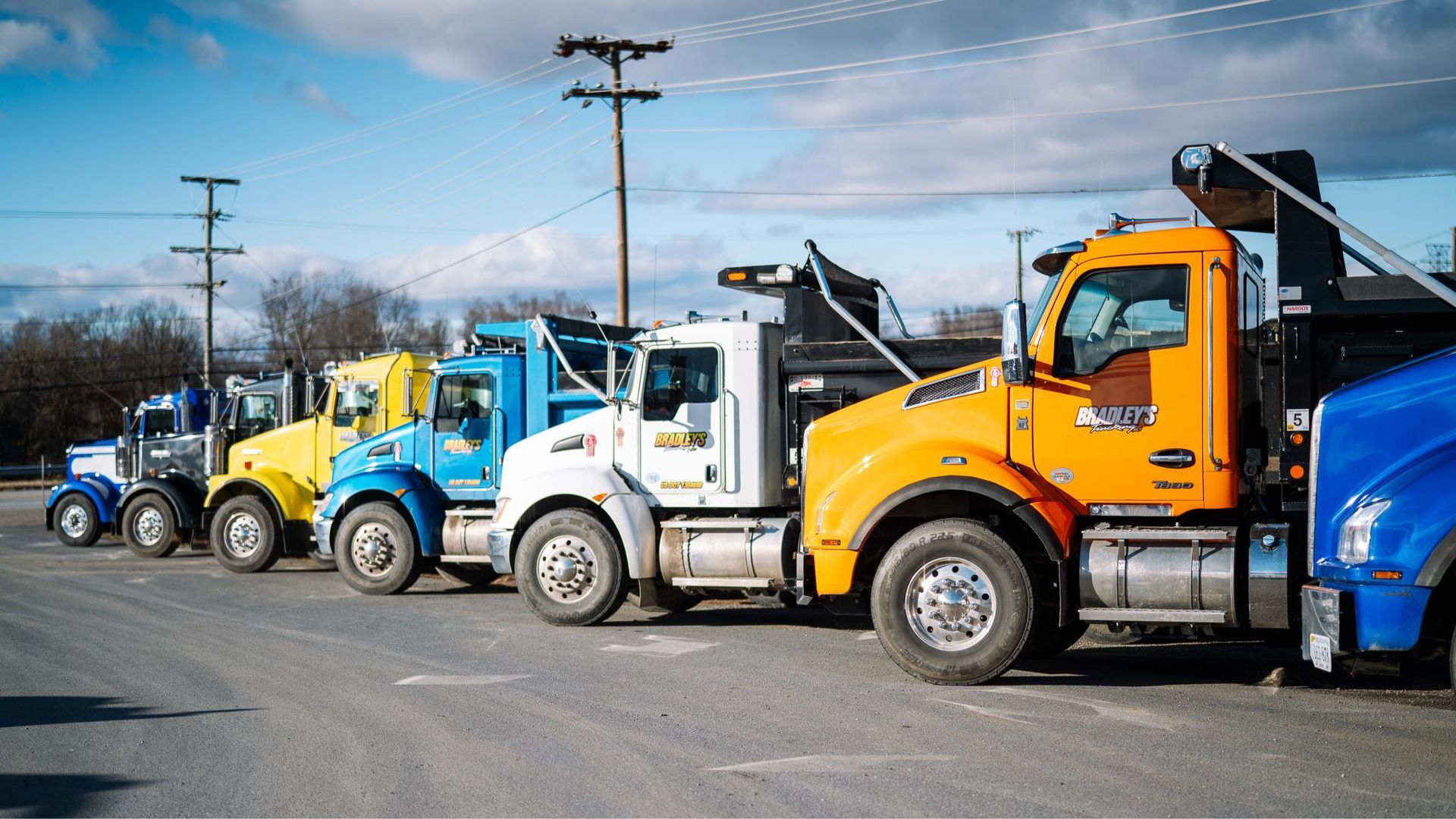 A row of trucks are parked in a parking lot.