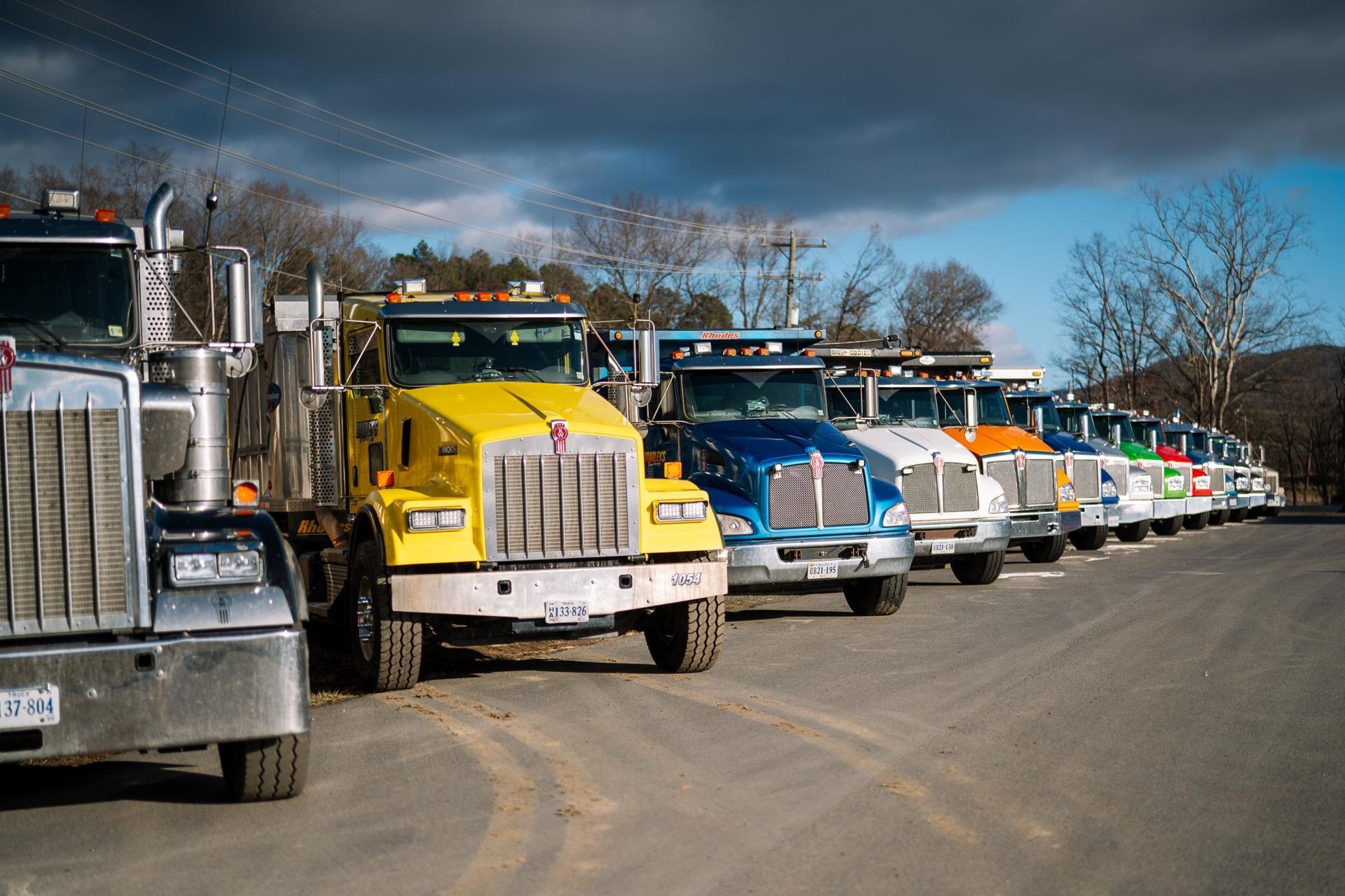 A row of trucks are parked in a parking lot.