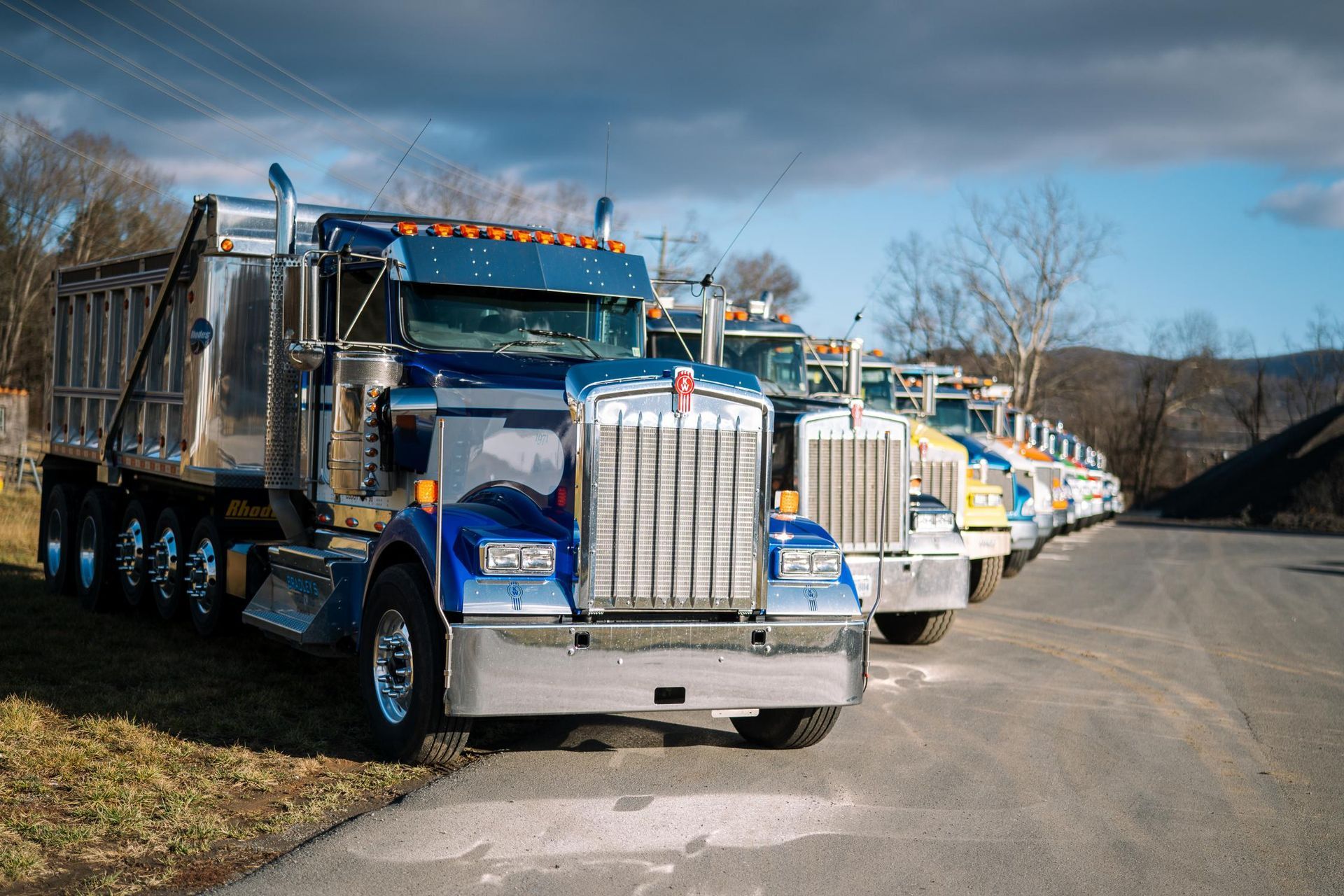 A row of dump trucks are parked on the side of the road.