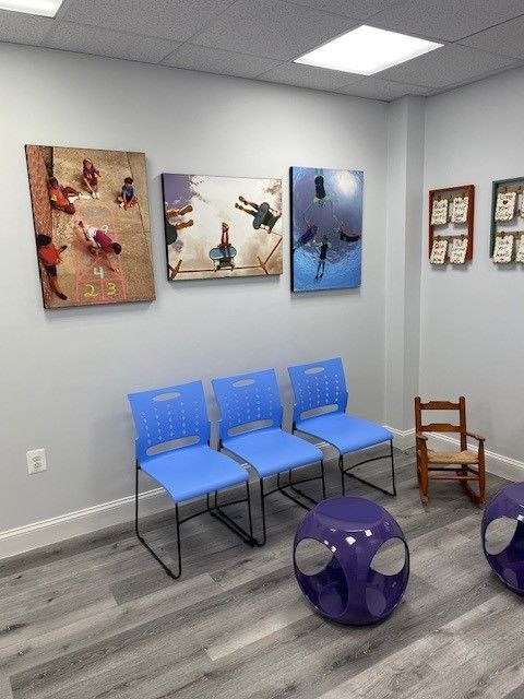 A waiting room with blue chairs and purple ottomans