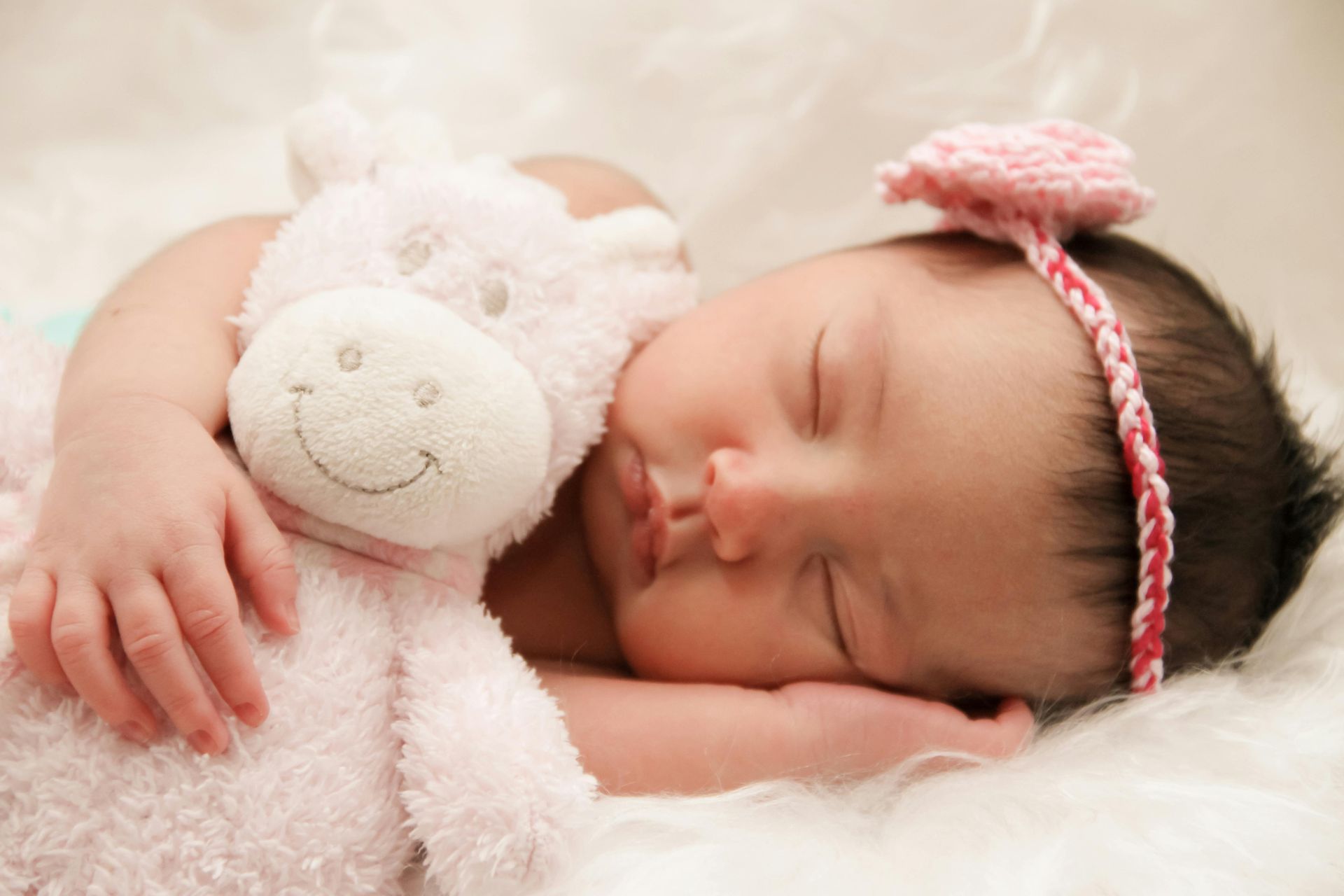 A baby is sleeping with a stuffed animal in her arms.